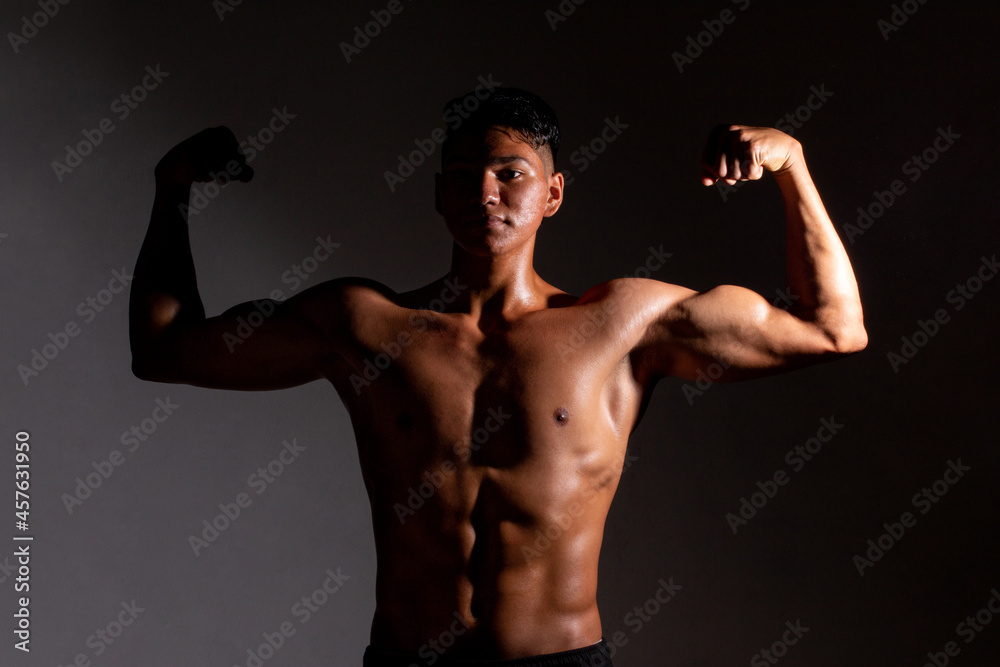 Slim and muscular young man posing with his naked torso. Man starting his muscle growth stage.