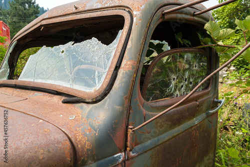 Windshield and driver side window with bullet holes on a rusty a