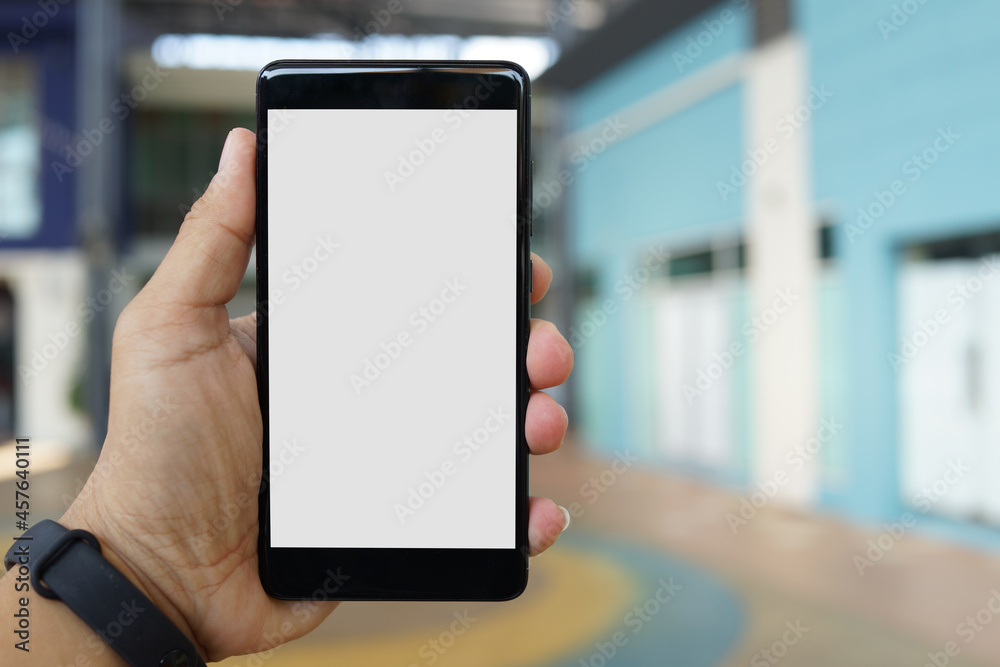 Adult hand holding a smartphone outside a store with blank copy space screen for text message or information content
