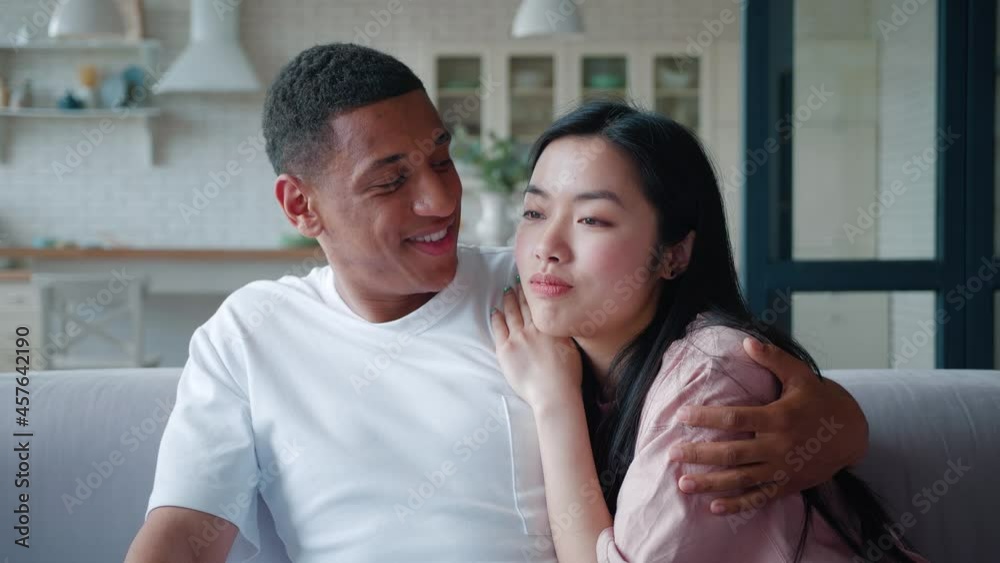Close-up confident portrait of a happy interracial young couple enjoying time together, African American guy gently embracing his Asian girlfriend leaning on his shoulders, communicating together Close-up confident portrait of a happy interracial young couple enjoying time together, African American guy gently embracing his Asian girlfriend leaning on his shoulders, communicating together