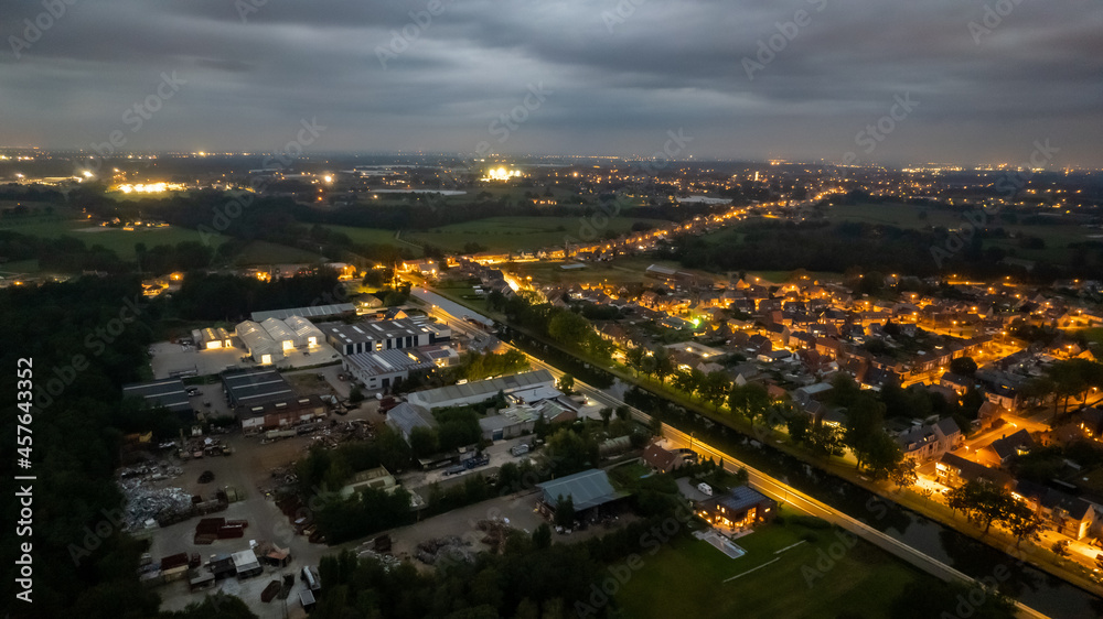 Aerial of a residential area seen from above during a dark grey cloudy sunset in Sint Jozef, Rijkevorsel, Antwerp, Belgium, shot by a drone. High quality photo