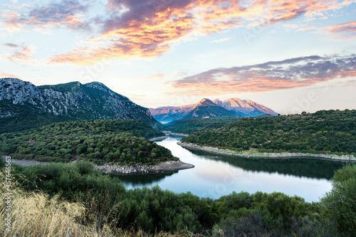 Stunning panoramic view of the Cedrino Lake (Lago del Cedrino) with the mountain range of Supramonte illuminated by a beautiful sunrise. Sardinia, Italy.