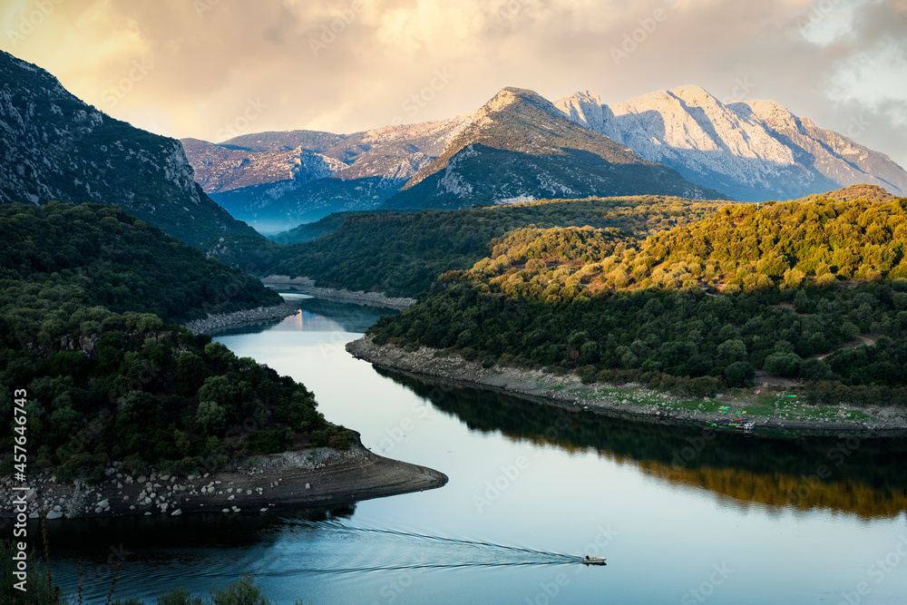 Stunning view of the Cedrino Lake (Lago del Cedrino) with the mountain range of Supramonte illuminated by a beautiful sunrise. Sardinia, Italy.