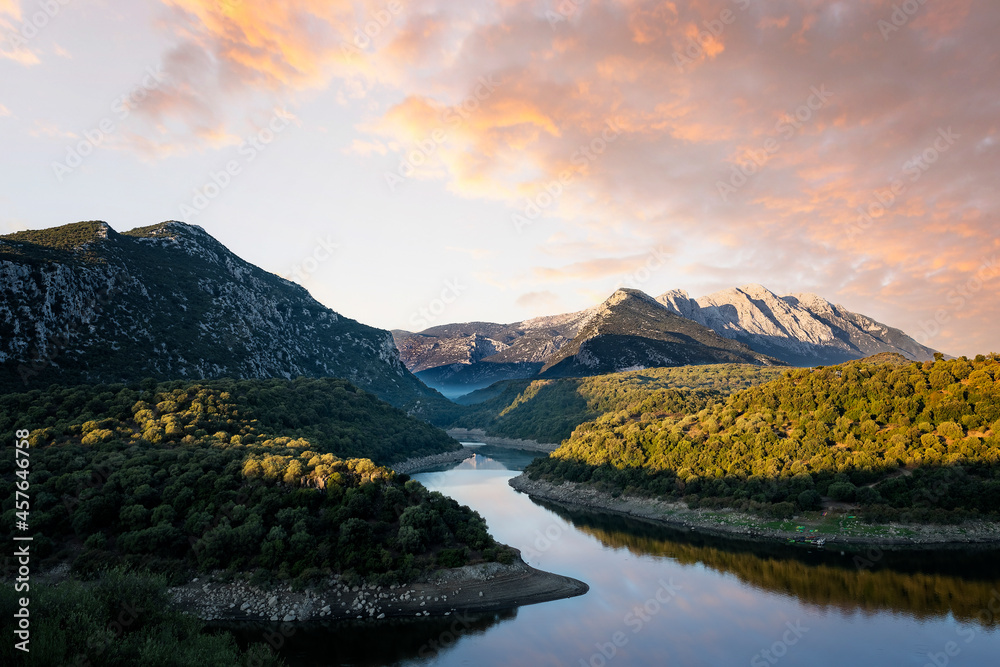 Stunning view of the Cedrino Lake (Lago del Cedrino) with the mountain range of Supramonte illuminated by a beautiful sunrise. Sardinia, Italy.