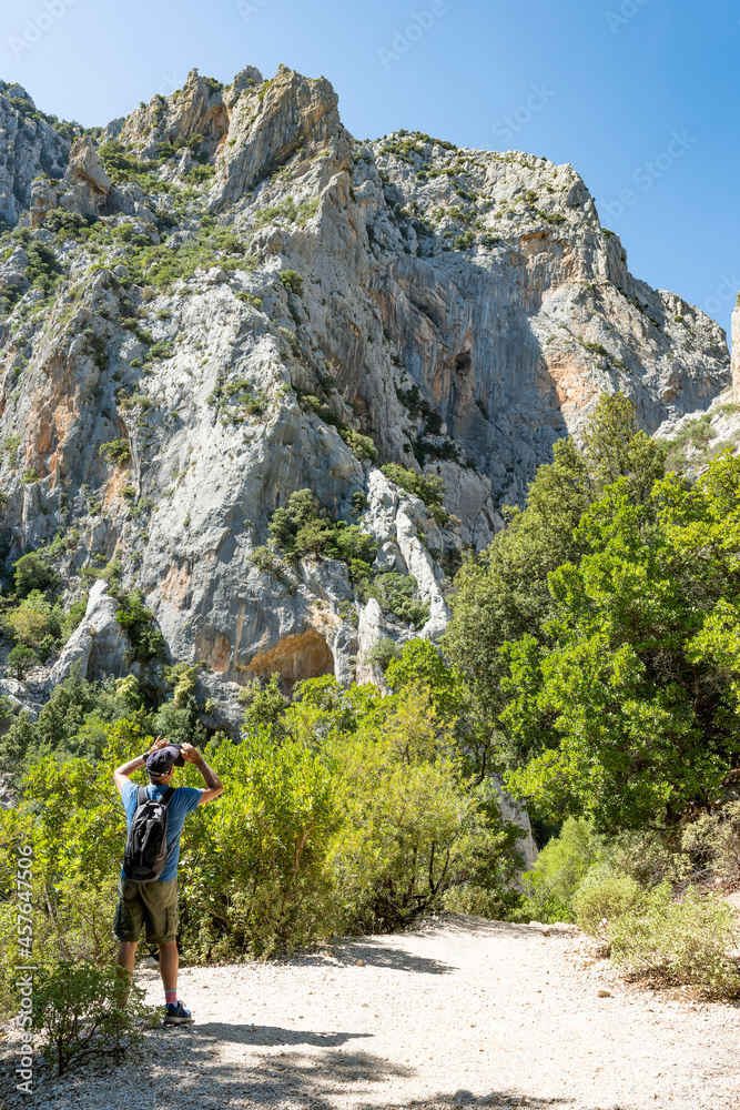 Stunning view of a tourist walking on a trail leading to Gorropu gorge. Gorropu is the most spectacular and deepest canyon in Europe and it is located in the Supramonte area, Sardinia, Italy.