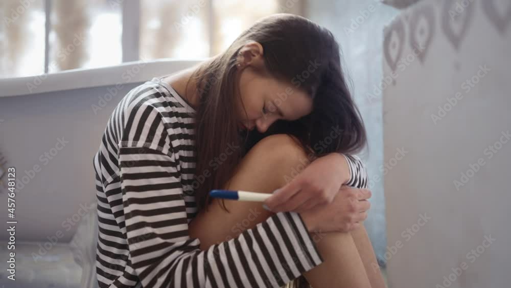sad girl sitting on the bathroom floor with a pregnancy test. the concept of a positive or negative pregnancy test or other problems related to the position and health of women sad girl sitting on the bathroom floor with a pregnancy test. the concept of a positive or negative pregnancy test or other problems related to the position and health of women