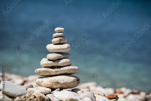 Balance pyramid of stones on the sea. Small pebble pillar. A symbol of calmness and tranquility. Close-up  blurred background.