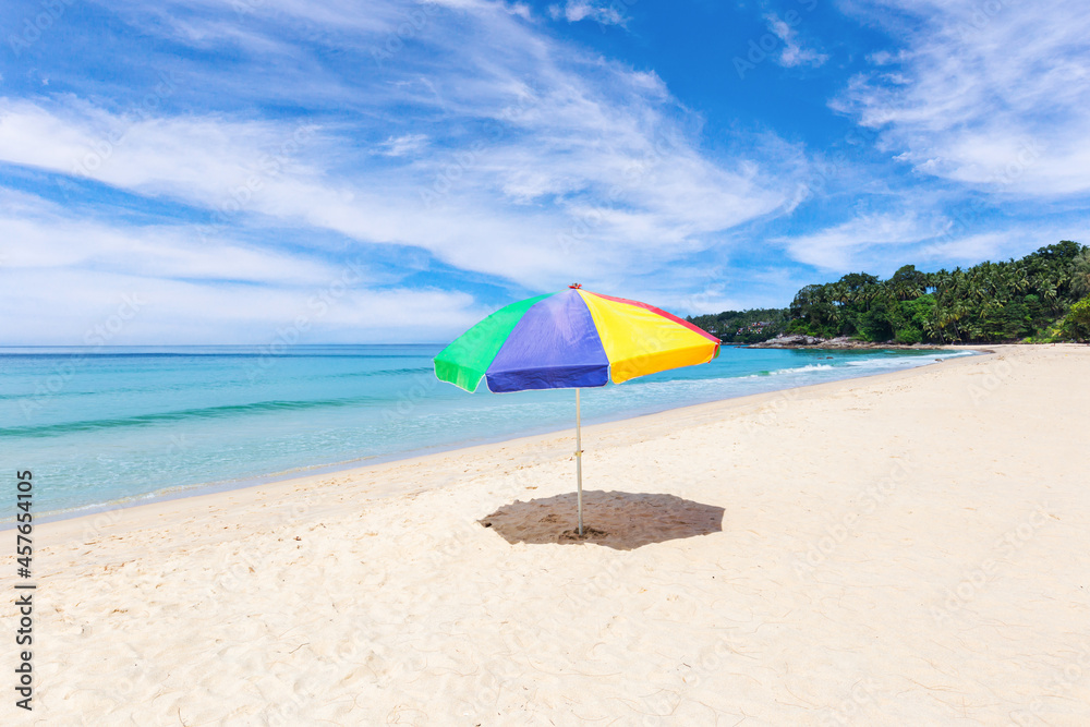 A colourful umbrella on white beach with beautiful sky.