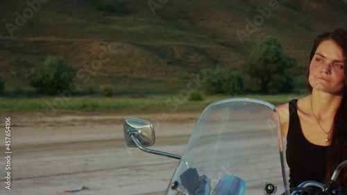 Young woman on a motorcycle looking at the sunset photo