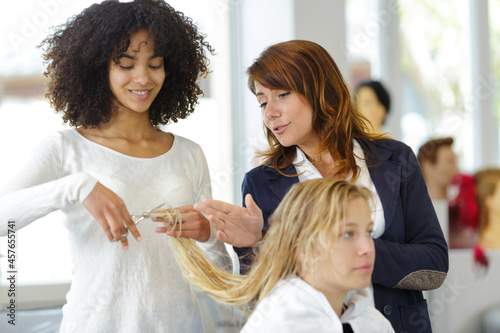 trainee hairdresser cutting clients hair