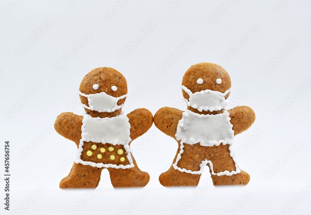 Cute gingerbread man and woman with protective face masks, white background. Creative concept in coronavirus (COVID-19) time