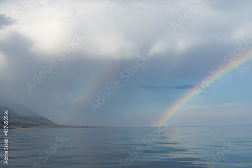 Double rainbow over the sea surface. Haze over the water. Wonderful seascape.