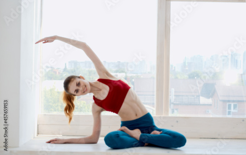 sportive woman doing yoga exercises near the window