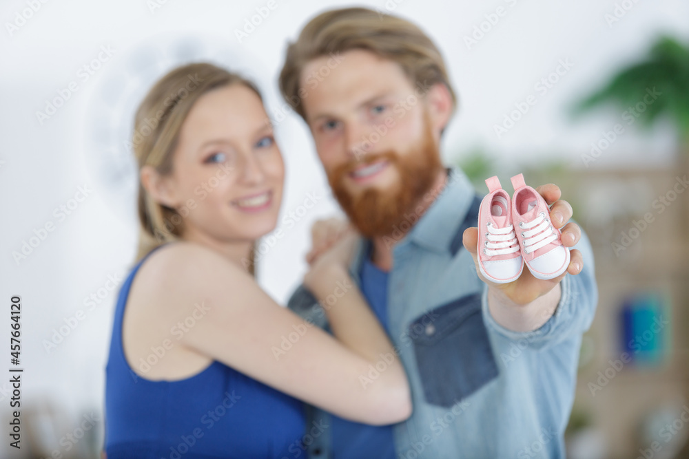 happy couple expecting baby holding baby shoes