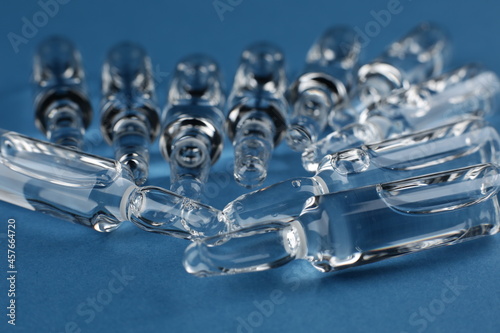 Glass vials with vaccine on blue background