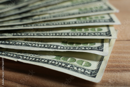 Lots of hundred dollar bills on wooden table