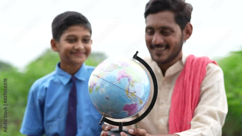 Indian farmer holding world globe in hand and giving some information to his child Indian farmer holding world globe in hand and giving some information to his child