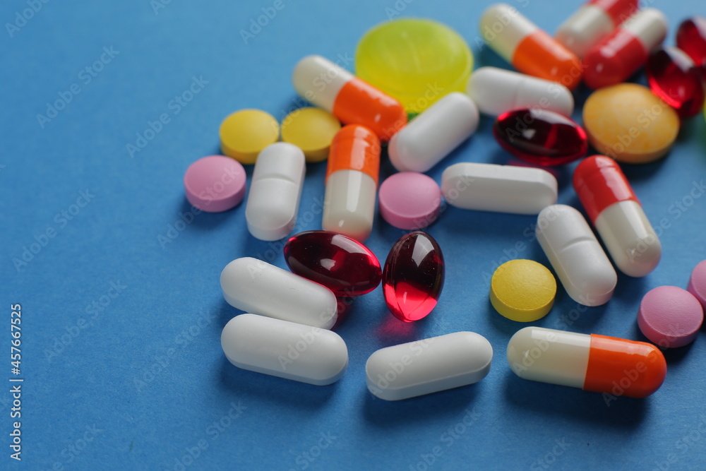 Multicolored medical pills of various shapes on a blue background Multicolored medical pills of various shapes on a blue background