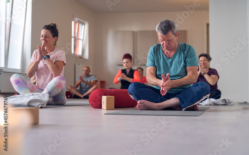 group, of different ages, in a yoga class, rubbing their hands together before beginning the practice of Yoga Mudra.