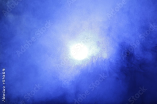 Artificial magic smoke in blue light on black background