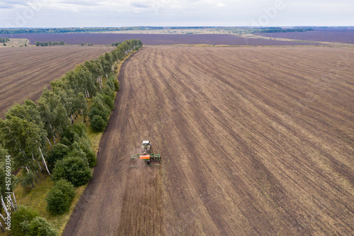 Aerial view of agricultural tractor with seeder machine at work on the field	 photo