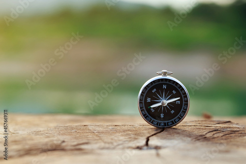 Magnetic compass standing upright on wooden with a natural background. conceptual of global travel, tourism and  travel with a compass and outdoor activities with compass