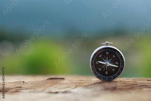 Magnetic compass standing upright on wooden with a natural background. conceptual of global travel, tourism and  travel with a compass and outdoor activities with compass photo