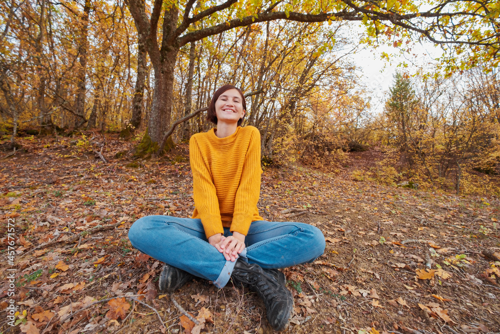 Woman hiking looking at scenic view of autumn foliage mountain landscape. Outdoor adventure travel lady sitting relaxing in nature in autumn season.
