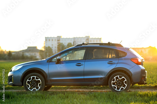 Landscape with blue off road car on green grass. Traveling by auto  adventure in wildlife  expedition or extreme travel on a SUV automobile. Offroad 4x4 vehicle in field at sunrise.