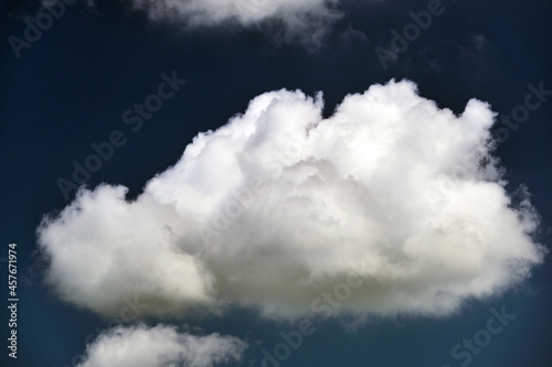 Bright landscape of white puffy cumulus clouds on blue clear sky.