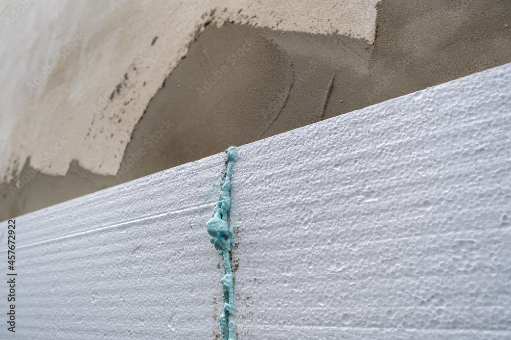 Obraz premium Installation of styrofoam insulation sheets on house facade wall for thermal protection.