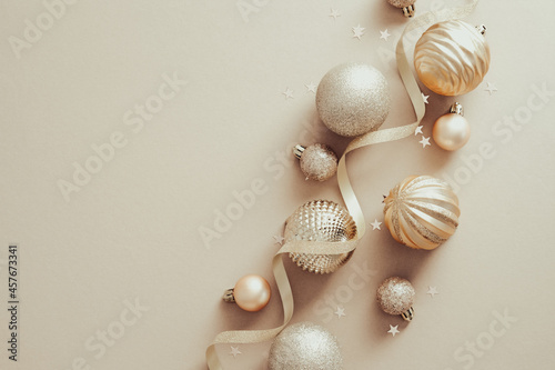 Stylish Christmas baubles and ribbon on beige background. Flat lay, top view.