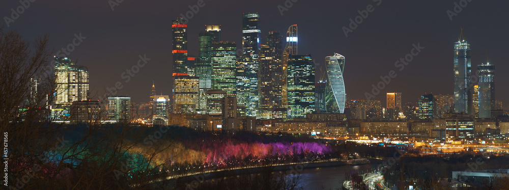 Long exposure photography of Moscow cityscape during winter night. Cold weather. Blurred lights of the city. Bright lighting of Moskva river embankment. Skyscrapers of Moscow business district