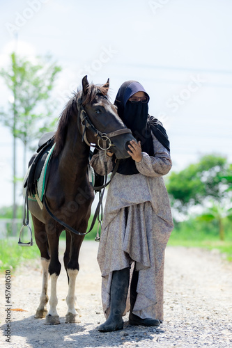 Portrait of Muslim woman with horse in the meadow