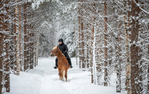 Woman horseback riding in winter in forest