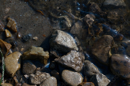 fuzzy background of stones on the sand and clear water