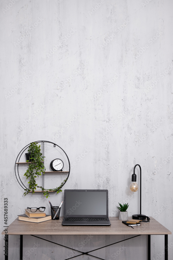 Workplace with laptop in office or home - copy space over concrete wall