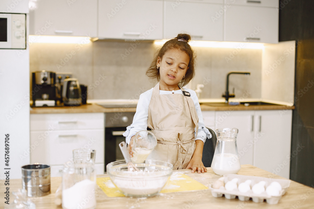 Child in a kitchen. Little girl with a dough. Kid in a beige apron Child in a kitchen. Little girl with a dough. Kid in a beige apron