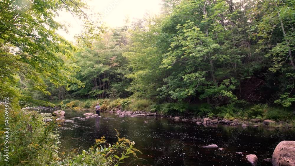 A young male fly-fisherman fishing on a beautiful trout stream. A young male fly-fisherman fishing on a beautiful trout stream.