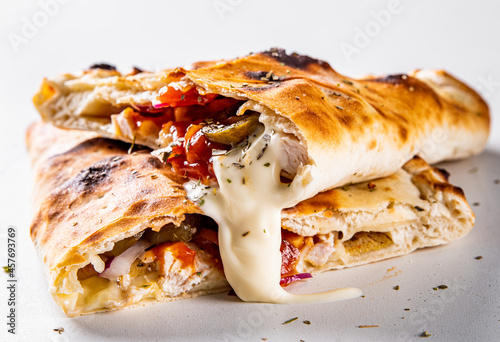Billede på lærred calzone pizza folded in half with meat, vegetables and cheese on a white backgro
