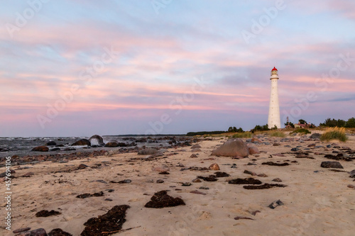Tahkuna lighthouse on the windy coast during sunset at Hiiumaa, Estonia, Europe. White lighthouse with red top on the rocky shore at sundown. Pink dawn near lighthouse on the shore.