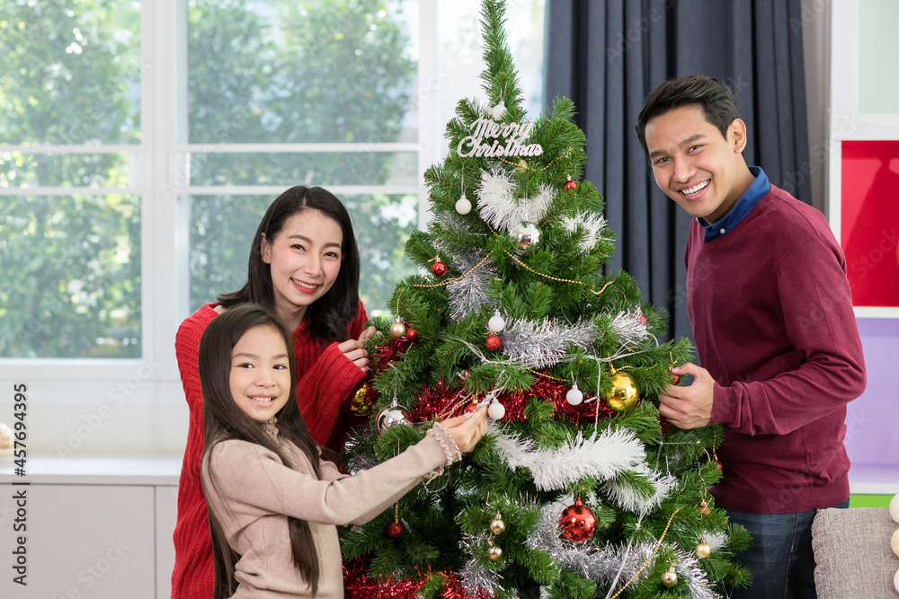 Merry Christmas, Happy young family and cute daughter little girl decorating Christmas tree at home, Christmas celebration concept Merry Christmas, Happy young family and cute daughter little girl decorating Christmas tree at home, Christmas celebration concept