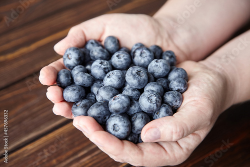 Blueberries in hands on wooden background closeup