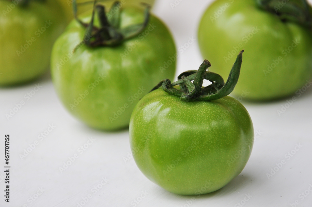 Green tomatoes on a white background. Some whole fresh green tomatoes, close up Green tomatoes on a white background. Some whole fresh green tomatoes, close up