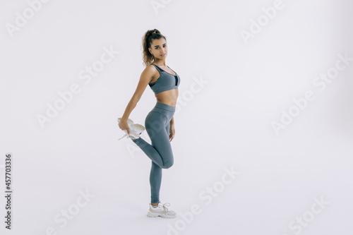 Fitness woman stretching full body. Fitness woman standing stretching thigh in full body isolated on white background.