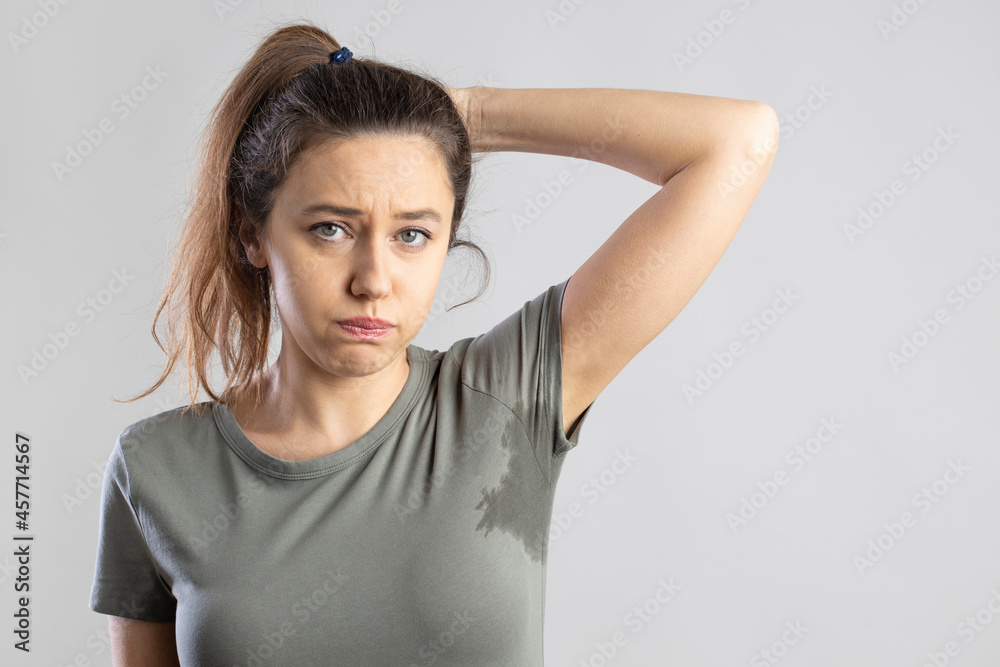 Young woman with her arm raised with her armpits sweat - obrazy, fototapety, plakaty 