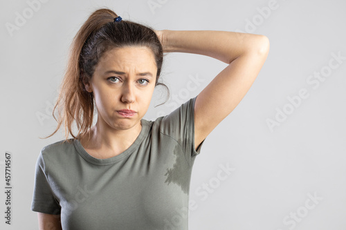 Young woman with her arm raised with her armpits sweat photo