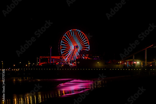 The lights of the Santa Monica Pier at night reflected in the Pacific Ocean. 