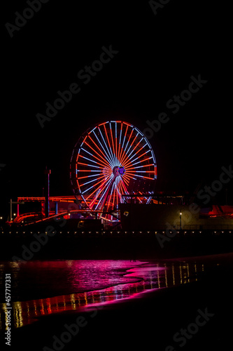 The lights of the Santa Monica Pier at night reflected in the Pacific Ocean. 