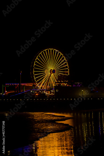 The lights of the Santa Monica Pier at night reflected in the Pacific Ocean. 